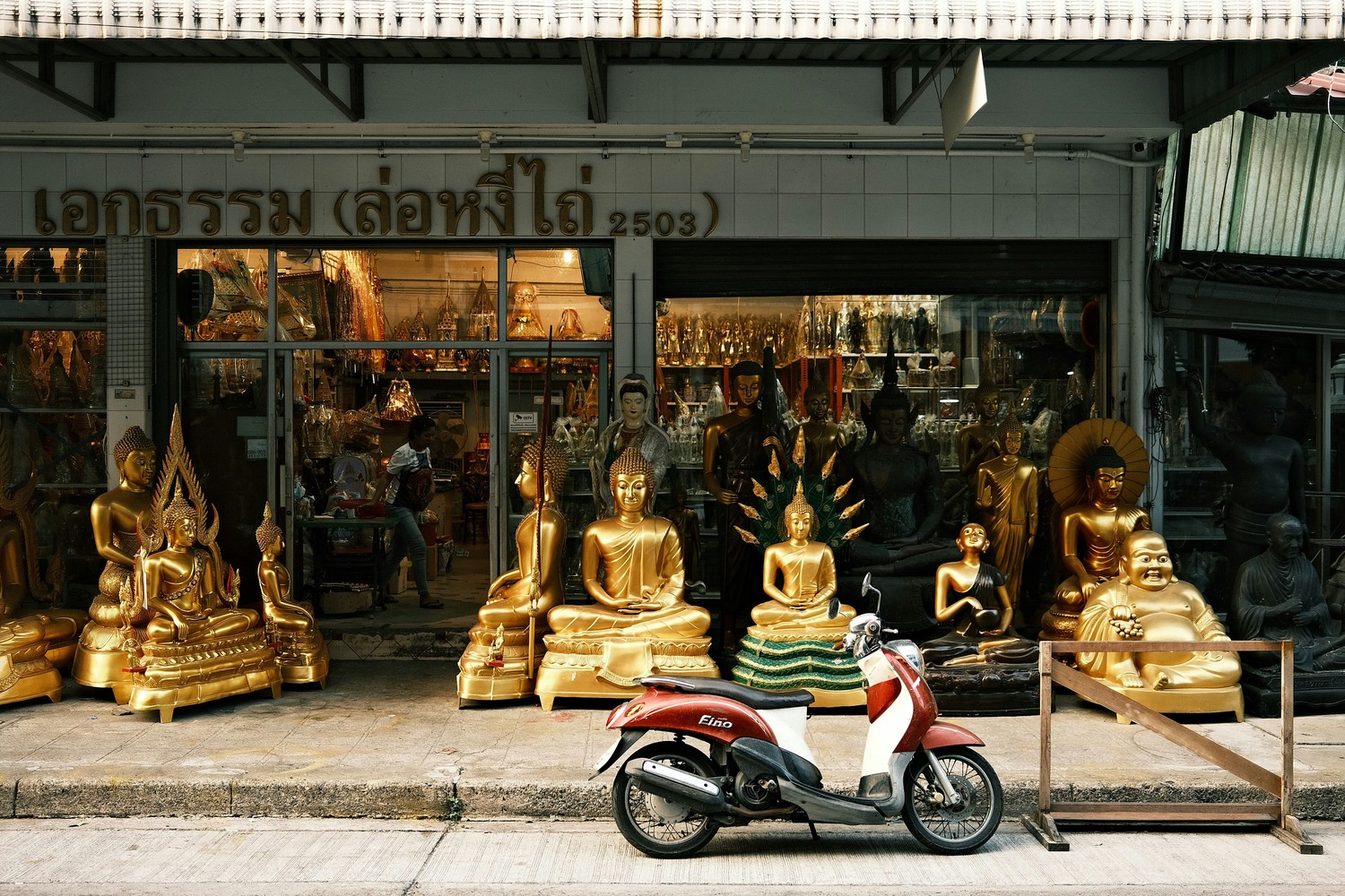 Scooter garé devant une boutique de statues de Bouddha en Thaïlande