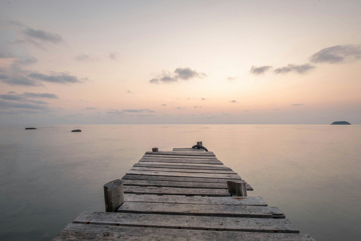 Ponton de bois s'avançant sur une mer étale au coucher du soleil, à Lonely Beach sur Koh Chang