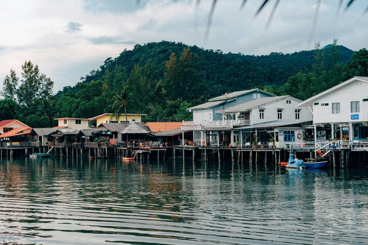 Maisons sur pilotis d'un village de pêcheurs de Koh Chang, au pied d'une colline boisée