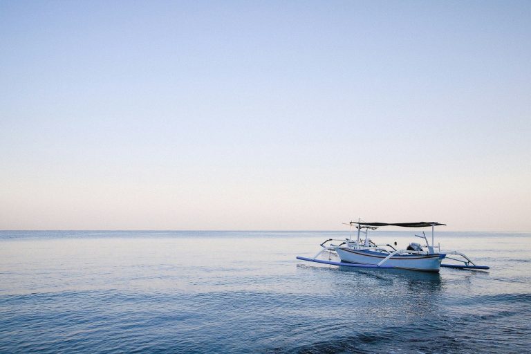 Bateau traditionnel jukung sur une mer plate au large de la côte nord de Bali