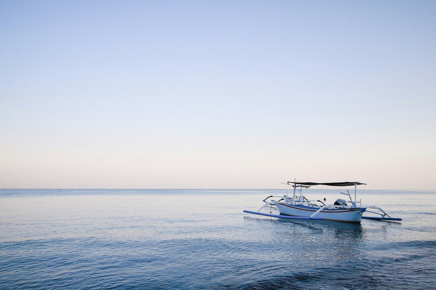Bateau traditionnel jukung sur une mer plate au large de la côte nord de Bali