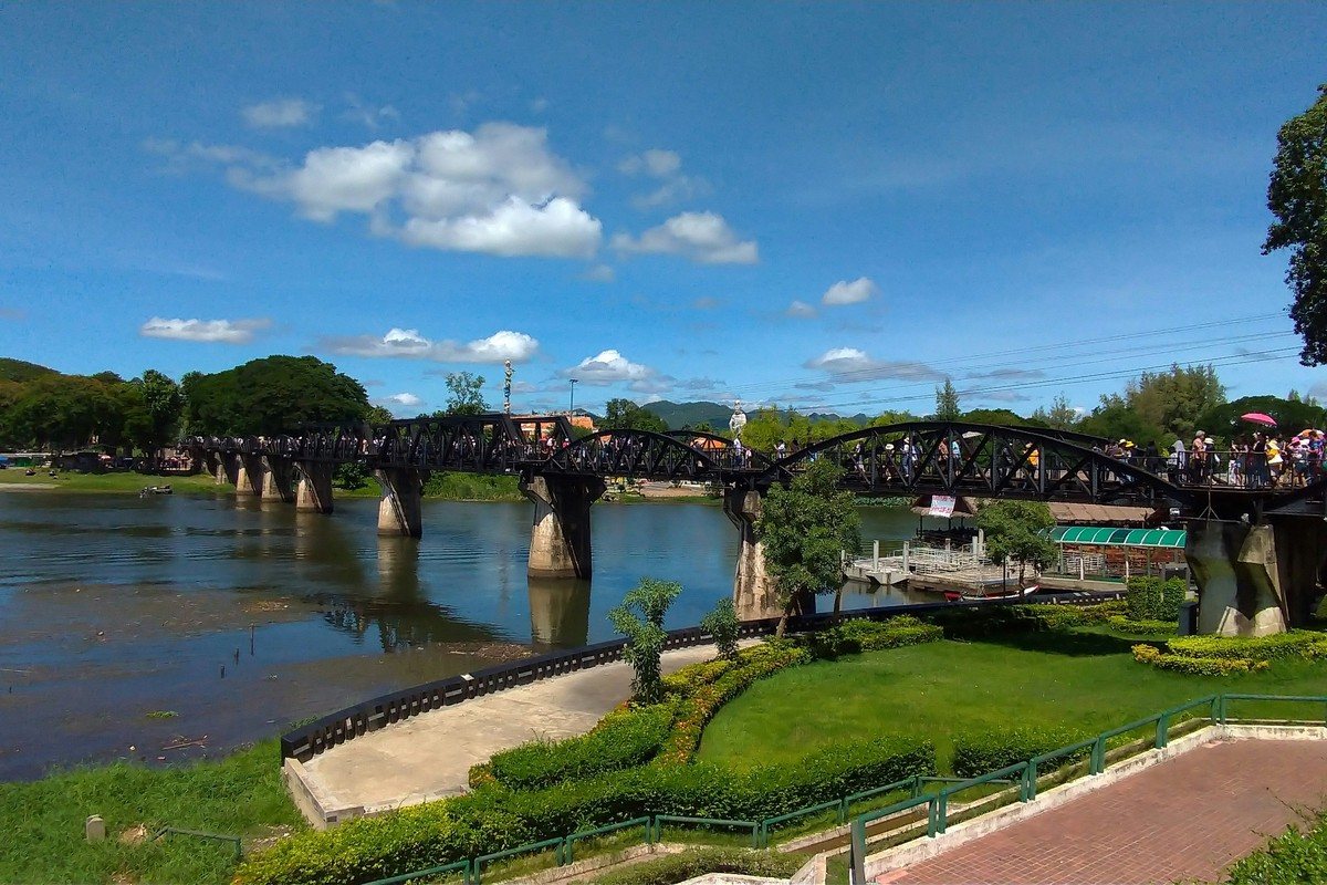 Le pont de la rivière Kwaï couvert de visiteurs, bordé de cafés flottants et de restaurants sur pilotis