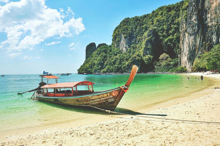 Longtail traditionnel échoué sur une plage de la côte Andaman, falaise calcaire en arrière-plan